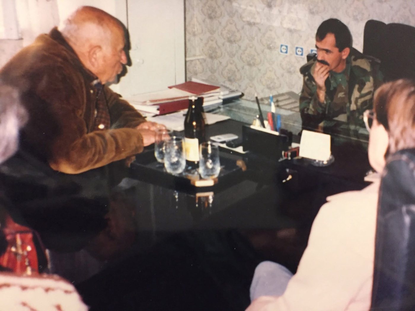 Charlie Melkonian seated at a low table across from Major General Nelson Soghomonyan, in camouflage fatigues, with Zabel Melkonian at right